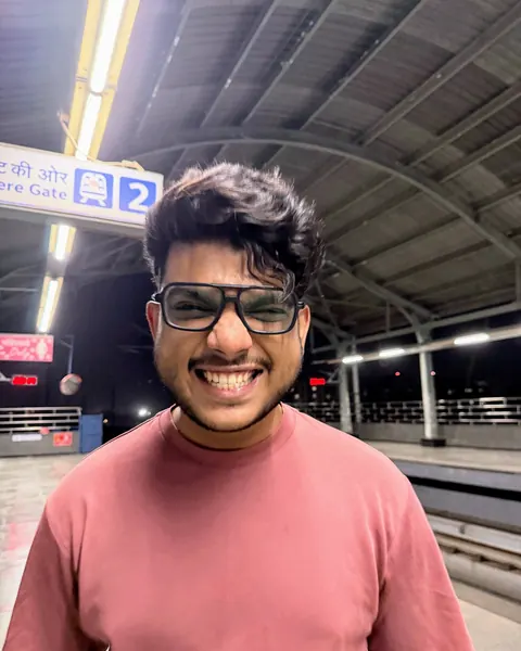 Ishaque grinning on a metro platform at night