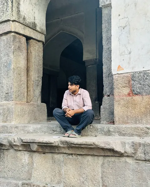 Ishaque sitting on the steps of an old stone monument