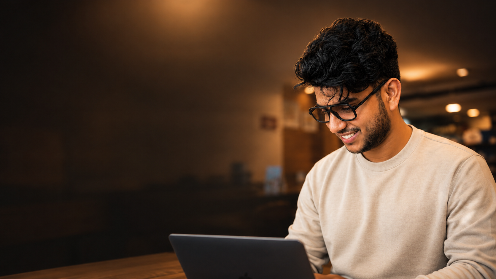 Ishaque Nv. smiling while working on a laptop